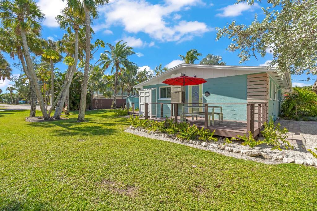 a tiny house with a deck and a red umbrella at MI Happy Place Sea Turtle 4 in Holmes Beach