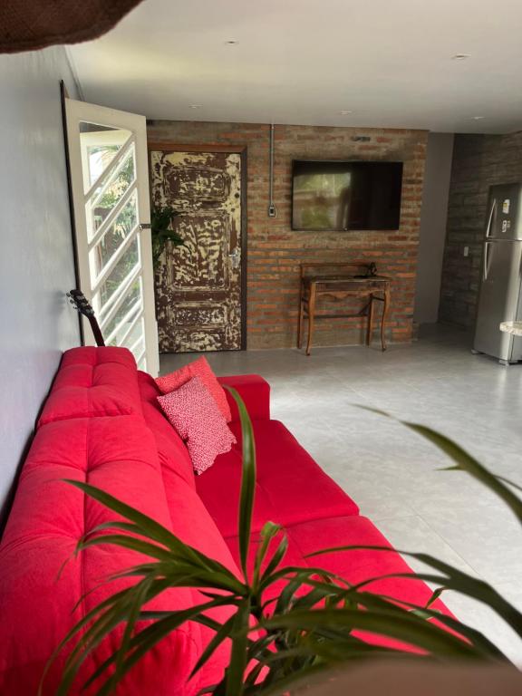 um sofá vermelho numa sala de estar com uma televisão em Pousada O Bosque Casa 1 em Imbituba