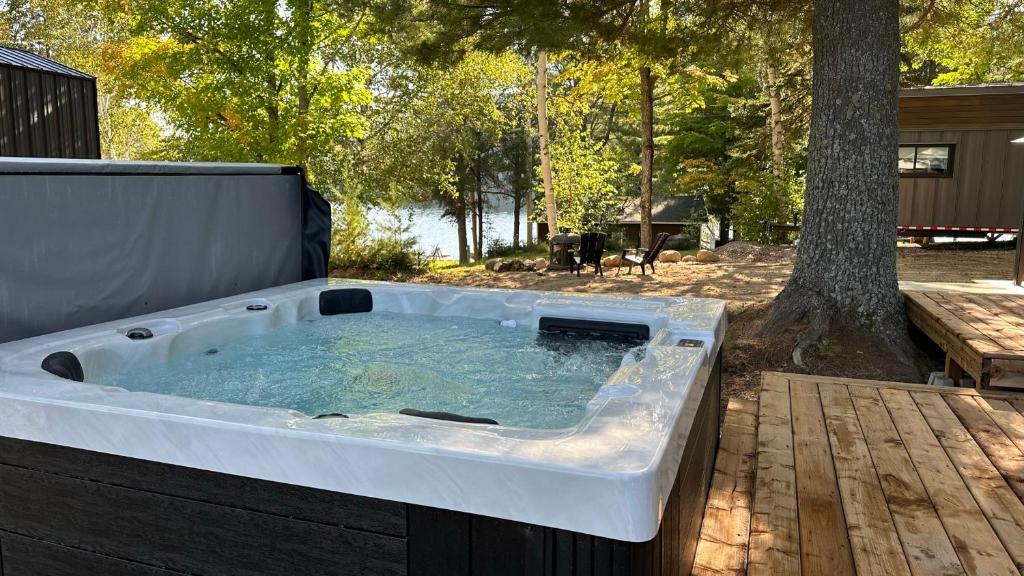 a hot tub sitting on a deck next to a tree at Micro chalet Le Boisé ! in Saint Zenon