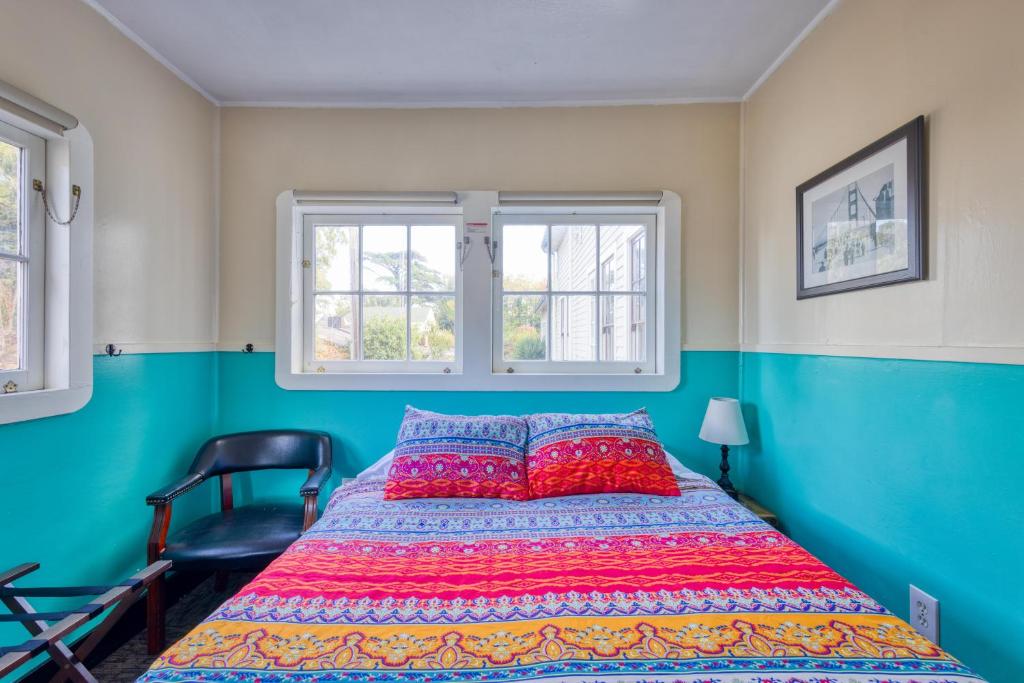a bedroom with a bed and a chair and two windows at HI San Francisco Fisherman's Wharf Hostel in San Francisco