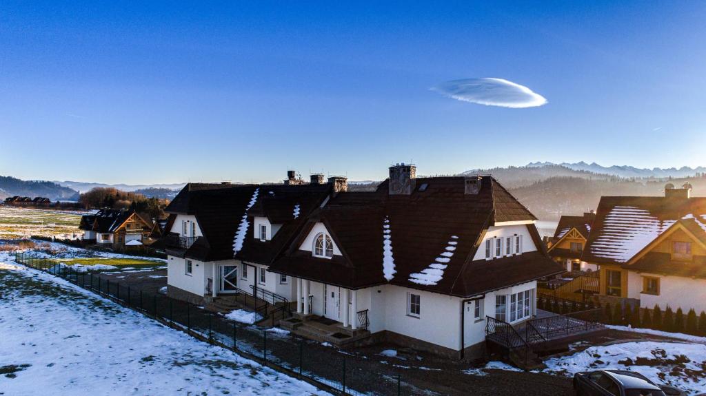 Un ufo vola sopra un gruppo di case nella neve di Pensjonat u Słodyczki - nad Jeziorem Czorsztyńskim a Kluszkowce