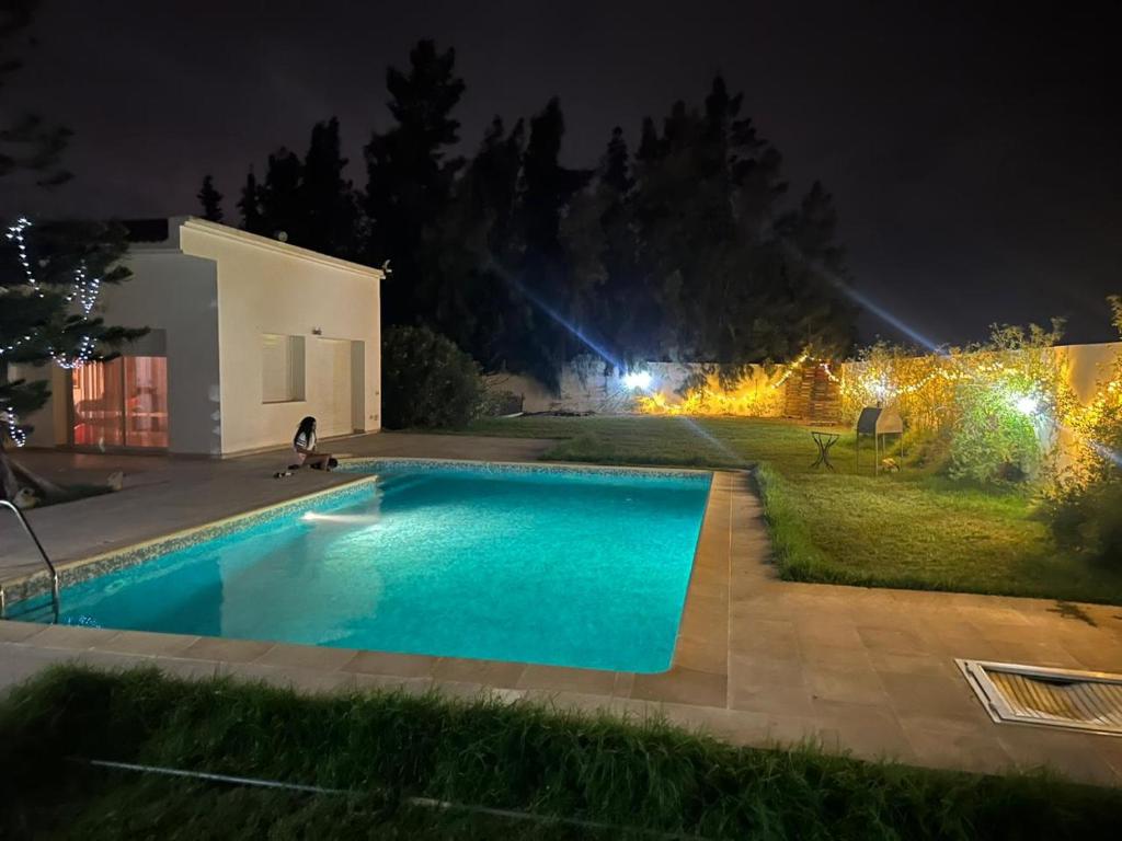 a swimming pool in a yard at night at Villa il Cavaliere in Douar Gabrejelli