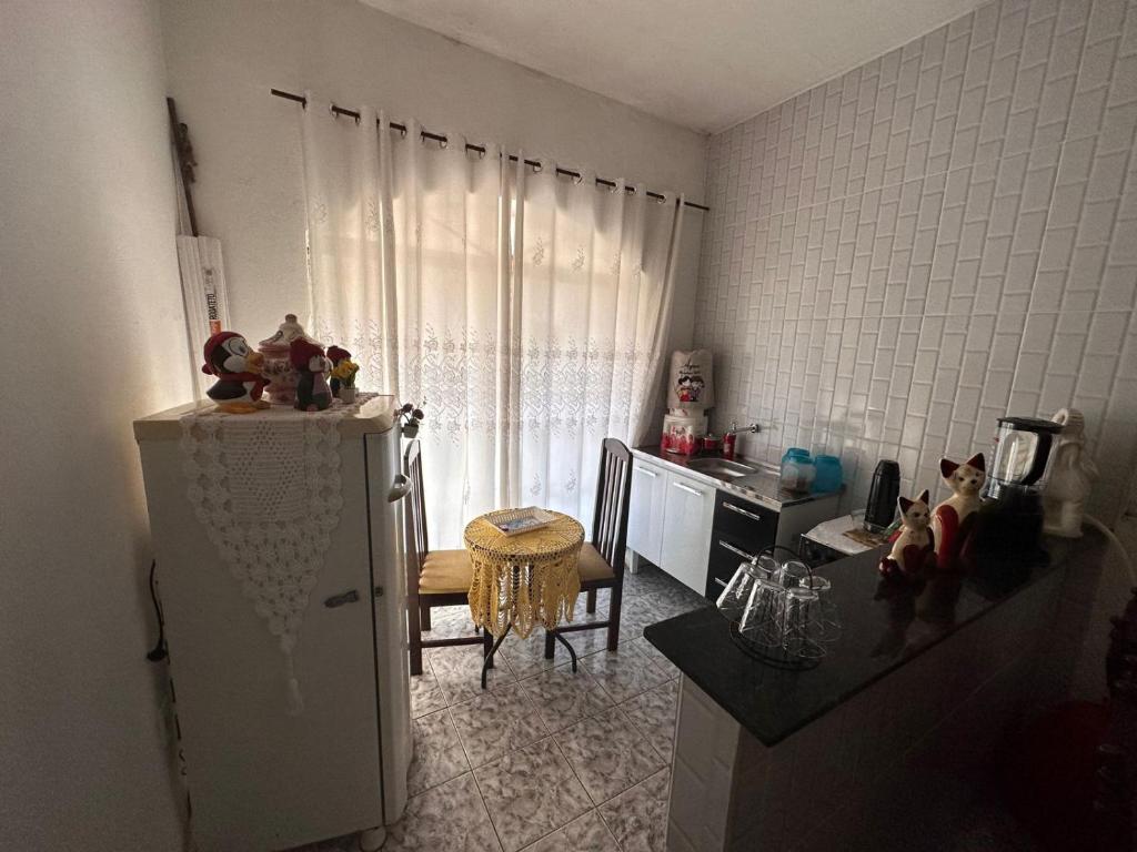 a kitchen with a refrigerator and a table with a counter at A CASA DE IRENE II in Aparecida