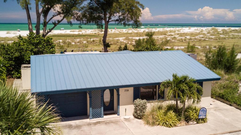a small house with a blue roof in front of the beach at Azure Seas in Anna Maria