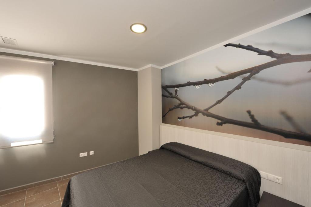 a bedroom with a bed with a tree mural on the wall at Aparthotel Meseguer in Alcañiz