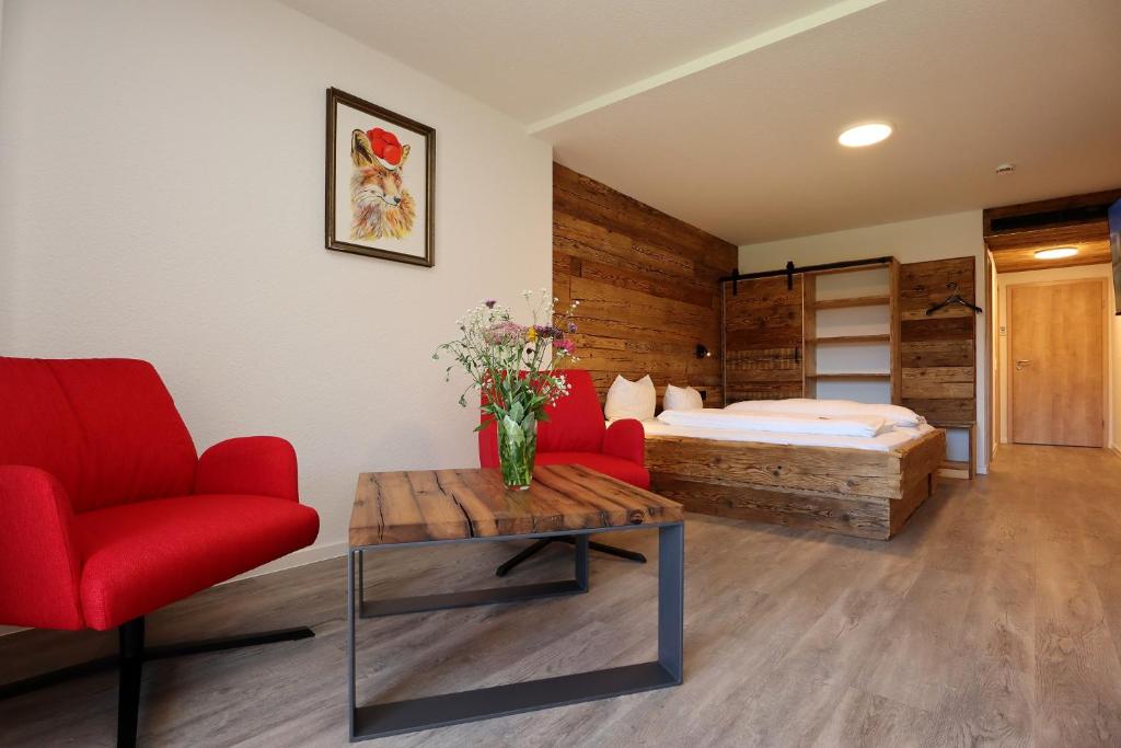 ein Schlafzimmer mit einem Bett, einem roten Stuhl und einem Tisch in der Unterkunft Landgasthof Adler Pelzmühle in Biederbach Baden-Württemberg