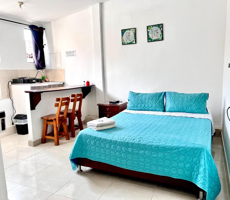 um quarto com uma cama azul e uma cozinha em Acogedor Apartaestudio en el Centro de Pereira em Pereira