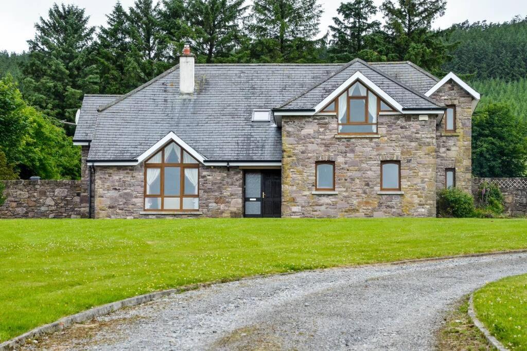 une grande maison en pierre avec une allée en gravier dans l'établissement The Mountain Lodge Slievenamon spacious 4 bedroom house, à Cloneen