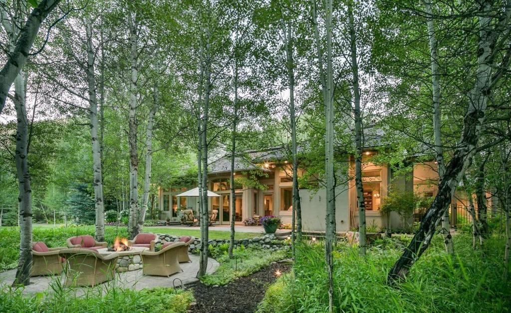 una casa en el bosque con patio y árboles en Riverfront Rainbow Bend Estate with Hot Tub, en Ketchum