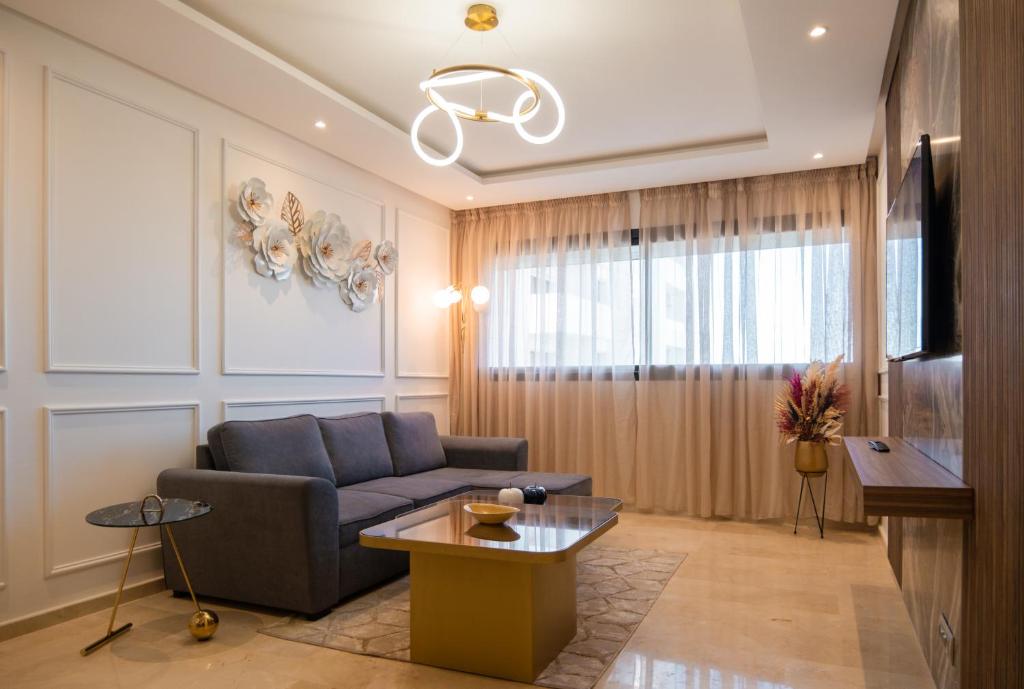 een woonkamer met een bank en een tv bij Appartement luxueux Prestigia in Rabat