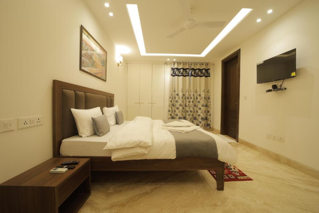 a bedroom with a large bed and a television at Under My Roof Superio in New Delhi