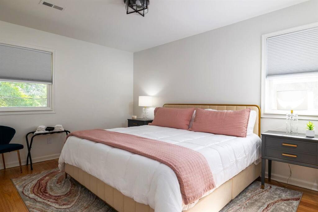 a bedroom with a large bed and two windows at Chic 2BR Durham Haven - Walk to Duke in Durham