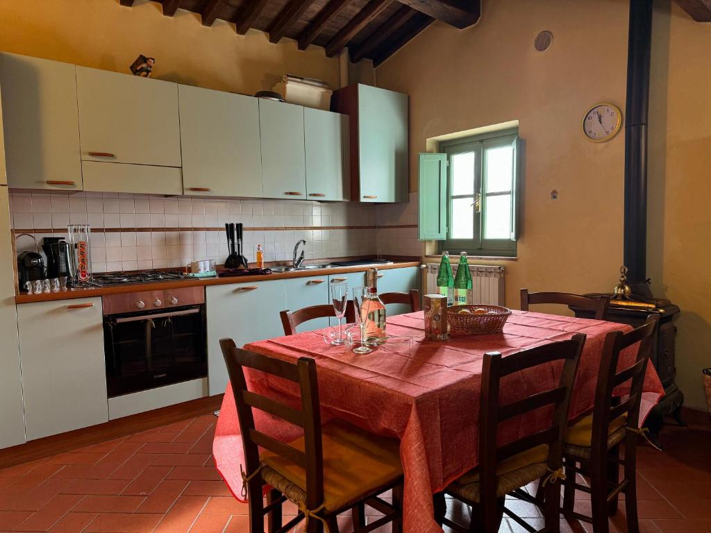 una cocina con mesa con sillas y una cocina con armarios blancos. en Podere il Casone, en Serravalle Pistoiese