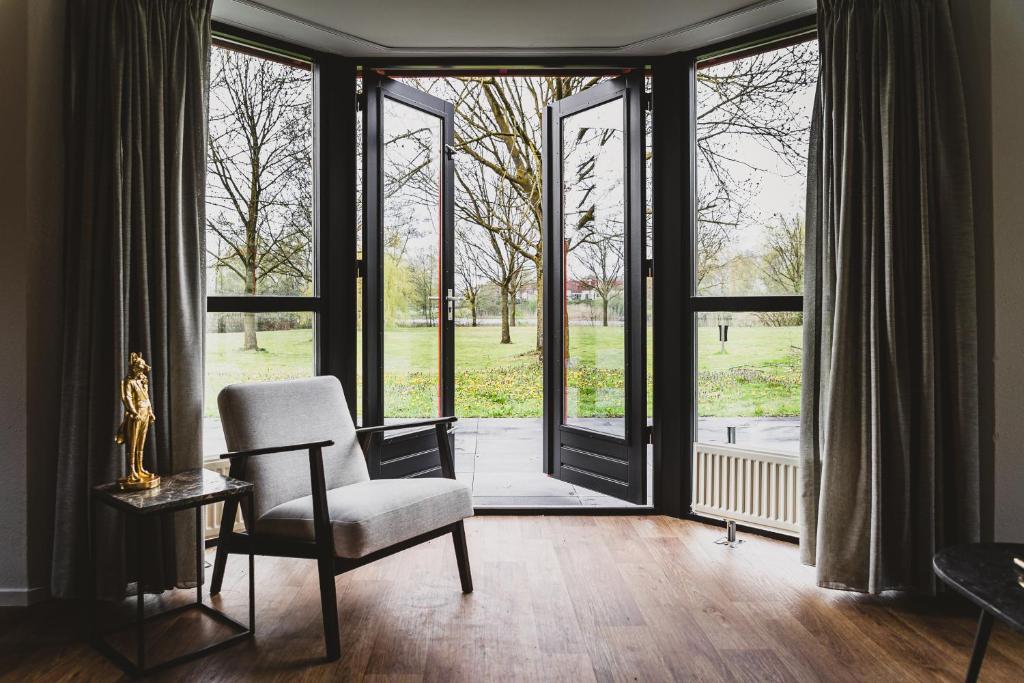 luxe vakantiehuisje - sauna - natuur - strand في Ewijk: غرفة معيشة مع كرسي وباب زجاجي منزلق