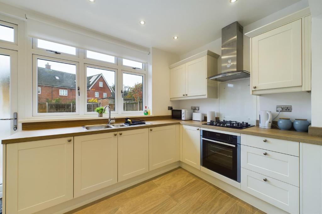 una cocina con armarios blancos y fregadero en Modern 3 Bed House, en Dagenham