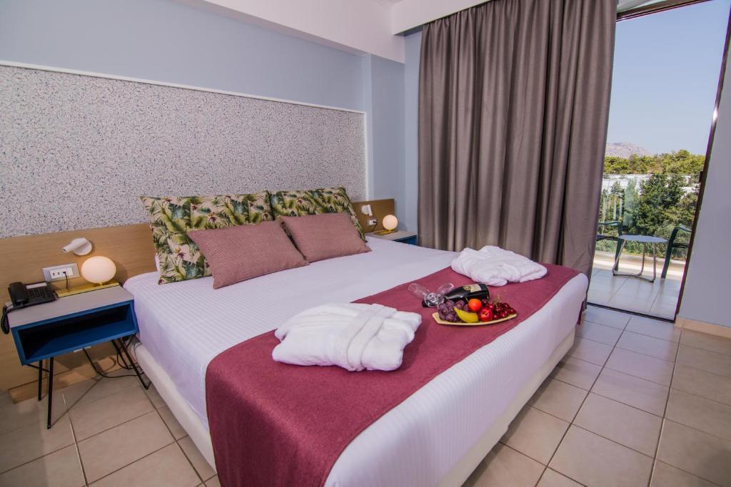 A bed or beds in a room at Lindos Breeze Beach Hotel