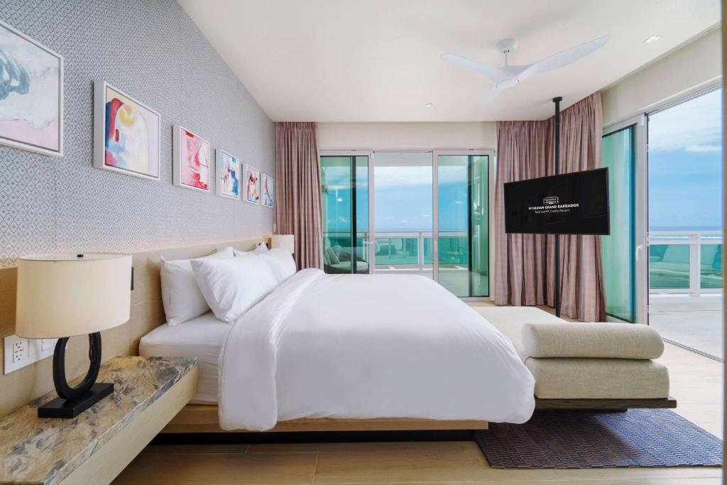 a bedroom with a large white bed and a window at Wyndham Grand Barbados Sam Lords Castle All Inclusive Resort in Saint Philip
