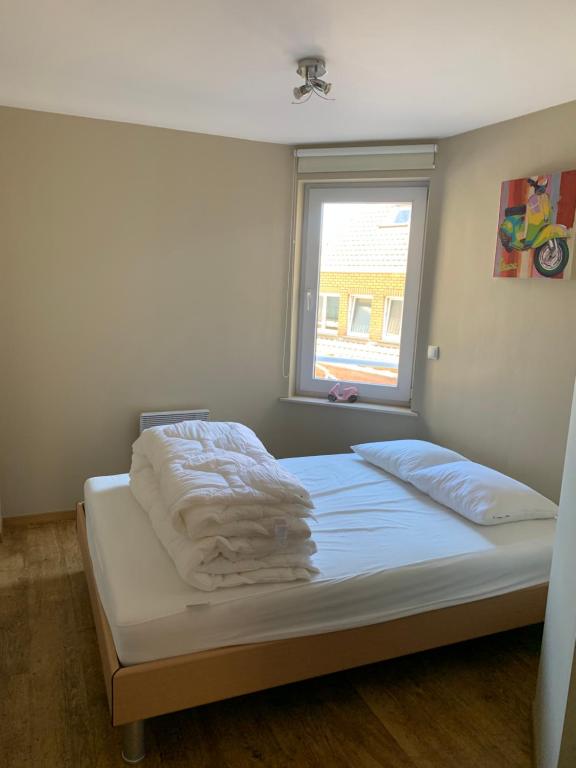 uma cama com toalhas num quarto com uma janela em ALMARE em Blankenberge