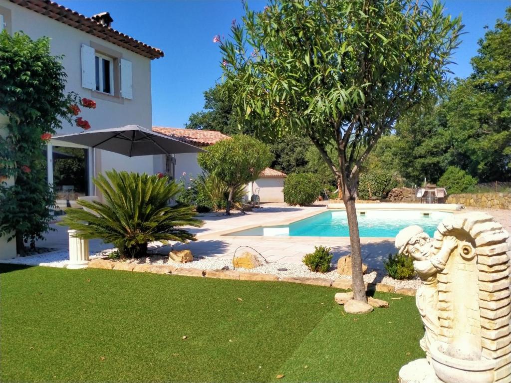 un jardin avec une statue à côté d'une piscine dans l'établissement Villa de standing tout confort PISCINE climatisation, à Montauroux