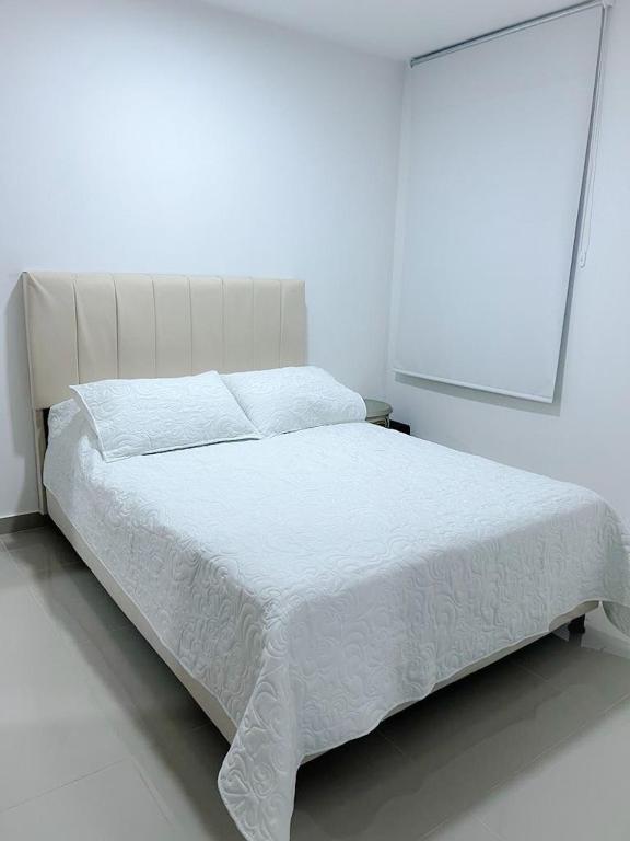 un letto bianco in una camera da letto bianca con copriletto bianco di Apartaestudio Amoblado a Valledupar