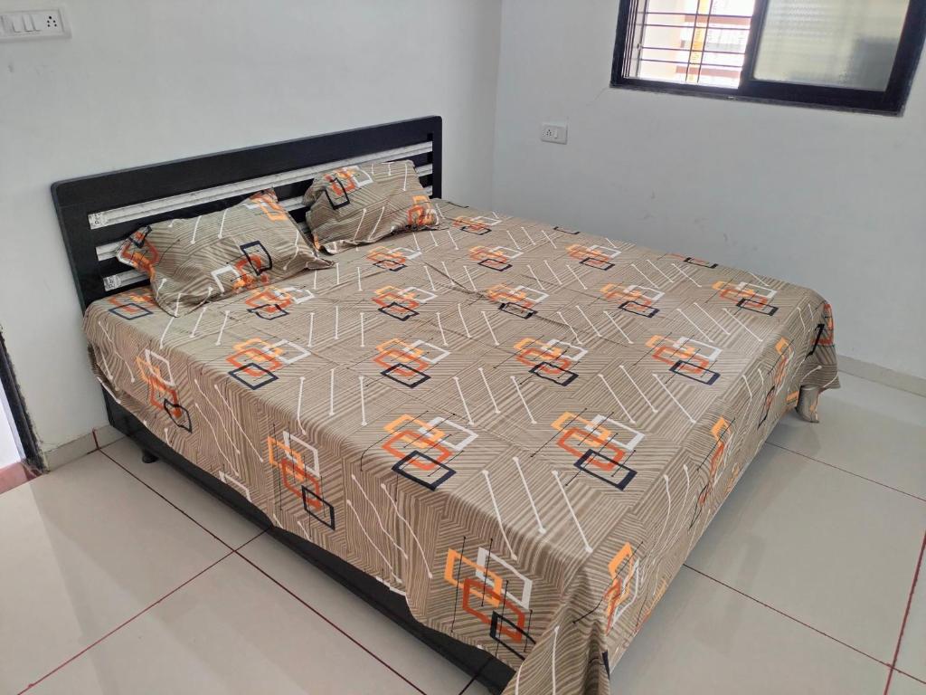 - un lit avec une couette brune dans une chambre dans l'établissement Ashapura Home Stay, à Kevadia