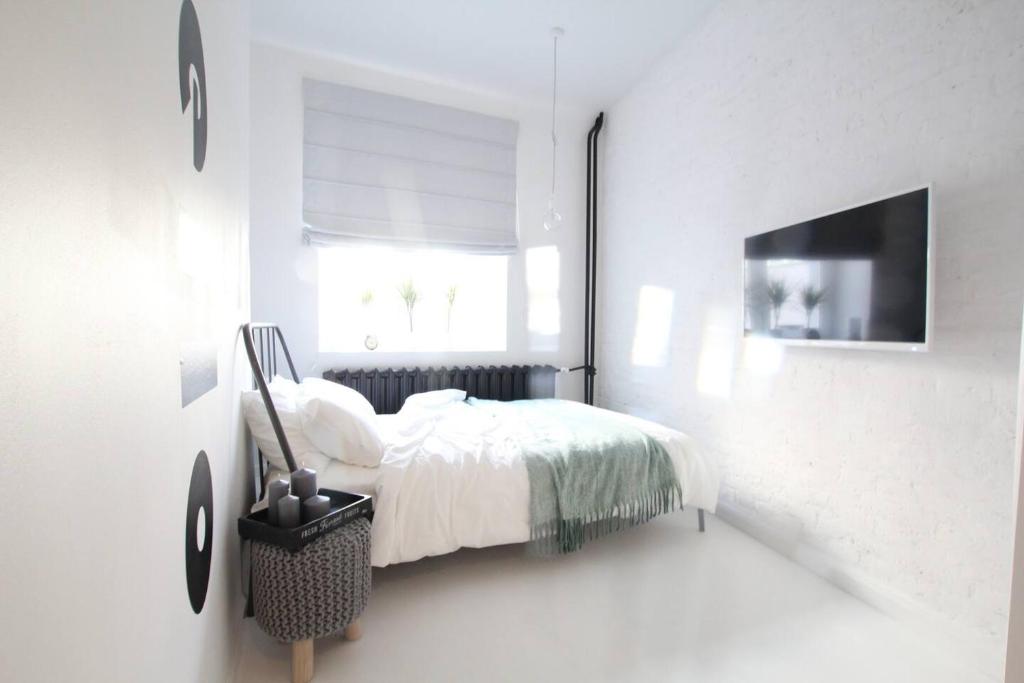 a white bedroom with a bed and a window at Bunga Apartament in Warsaw