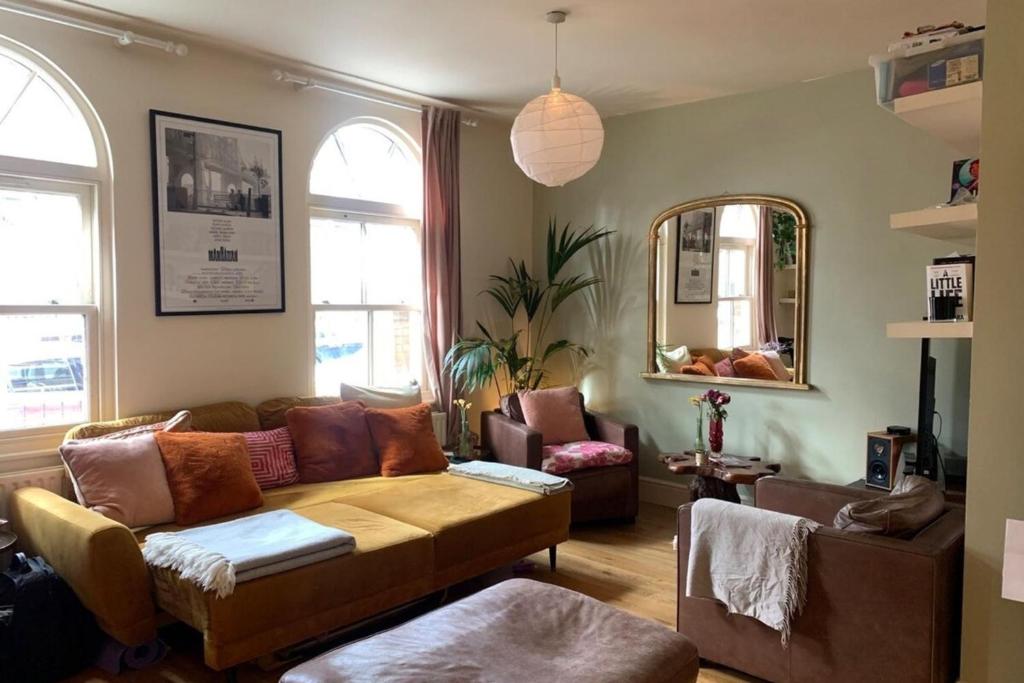 een woonkamer met een bank en een spiegel bij Stylish & Homely 1BD Flat 1min to Clapton Sqaure! in Londen