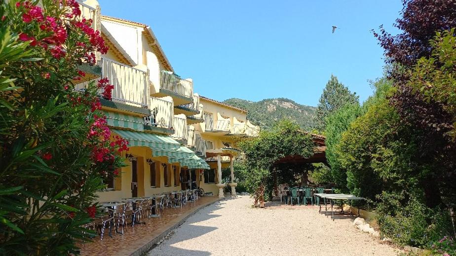 un vicolo con tavoli e sedie in un edificio di Hôtel Sous l'Olivier a Buis-les-Baronnies