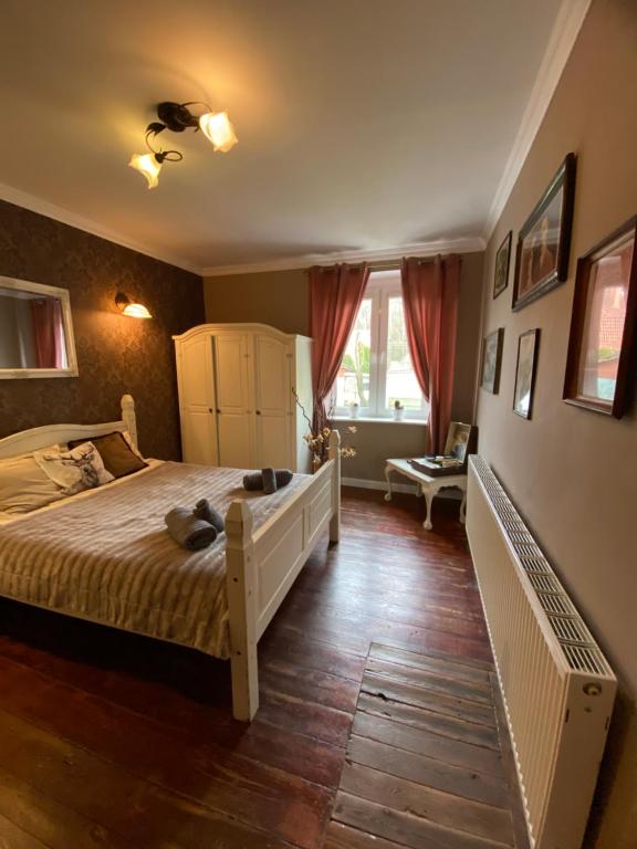 a bedroom with a large bed with a wooden floor at The Old House in Malbork