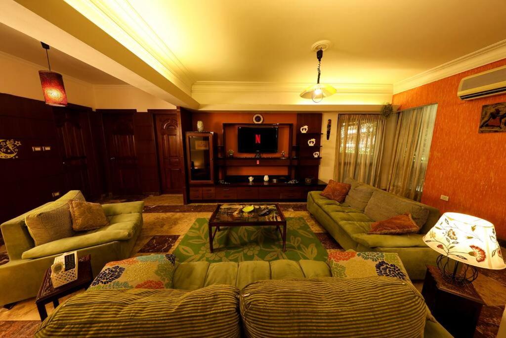a living room with a couch and a table at Luxury Apartment 6 min to Airport snacks included. in Cairo
