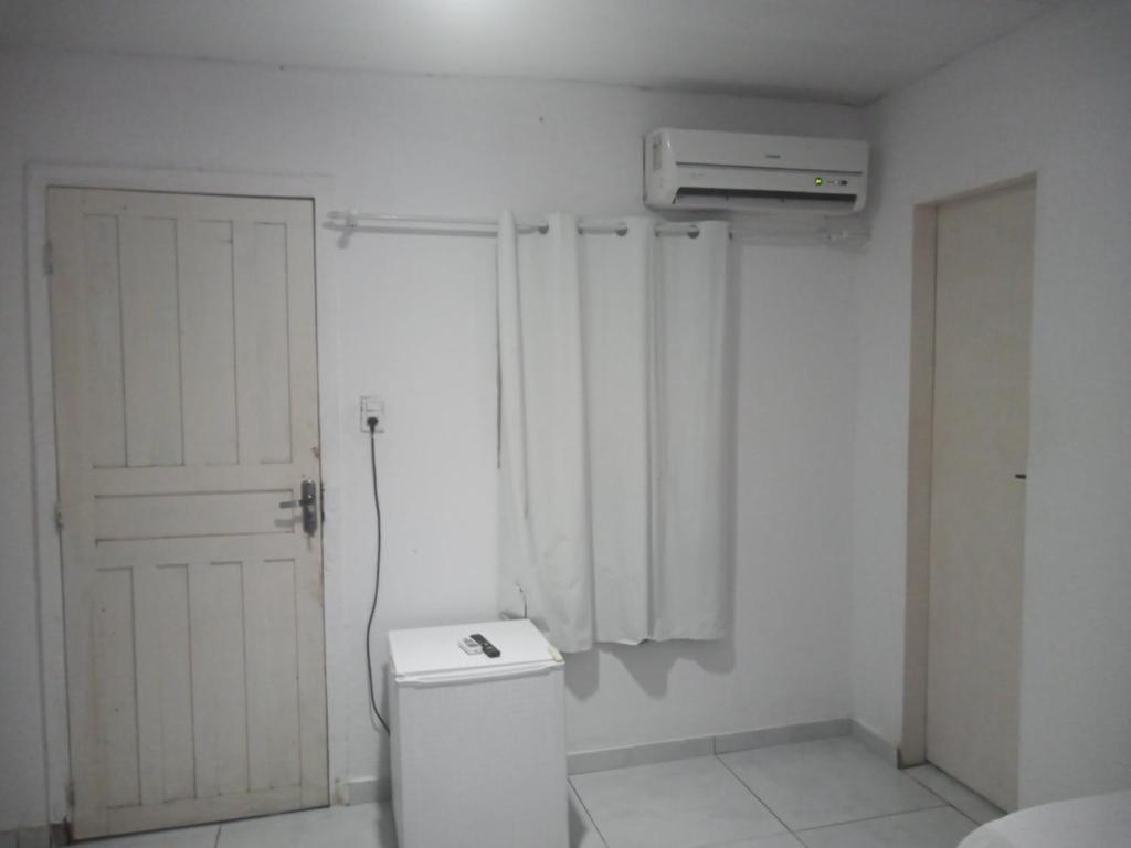 a white bathroom with a toilet and a air conditioner at Pousada Encontro das Águas in Paripueira