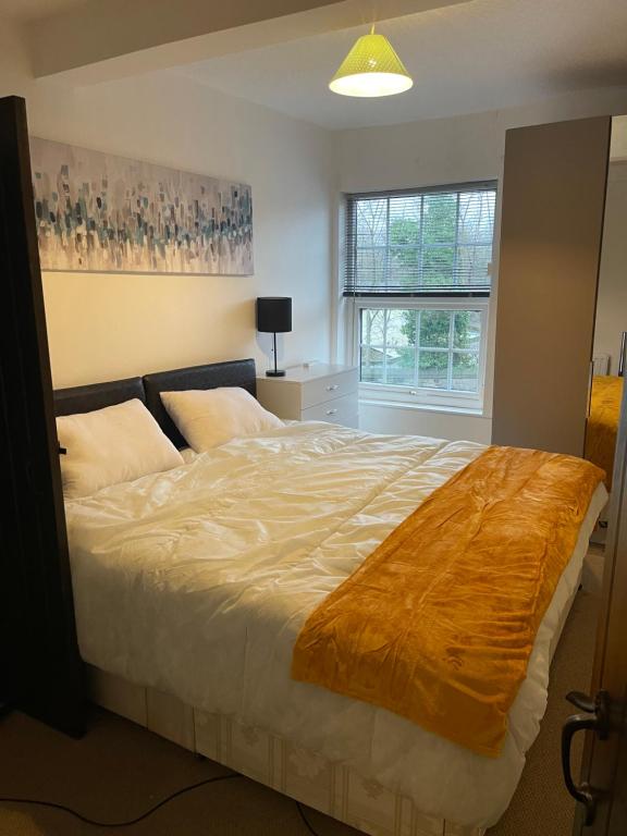 a bedroom with a large bed with a blanket on it at Stylish 3-Bed Gem in Romiley Newly Renovated, En Suite Comfort, Courtyard Charm, and Effortless Parking in Romiley
