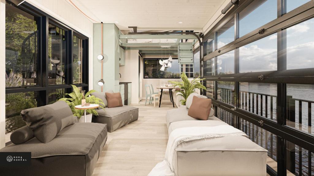 einen Balkon mit Sofas, einem Tisch und Fenstern in der Unterkunft MiniBora Le marin - Cantons-de-l'Est in Bury