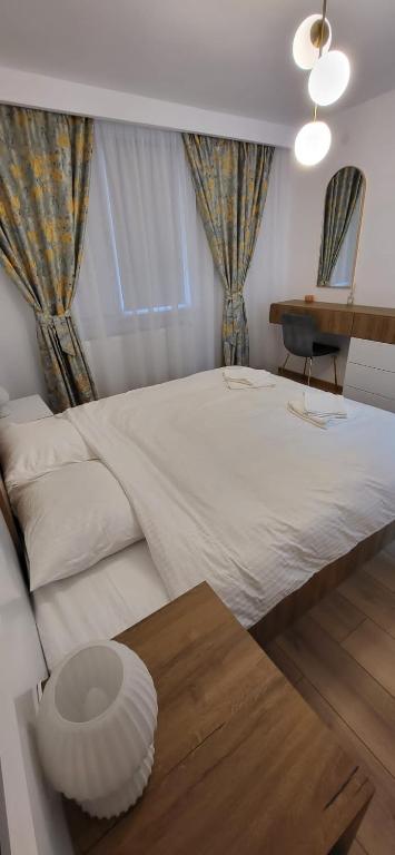 una camera da letto con un grande letto bianco e un tavolo di Urban Retreat Central - One bedroom apartment a Piteşti