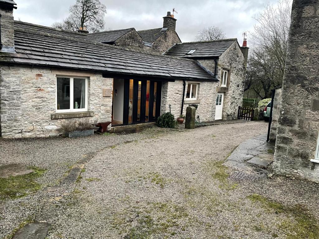 an old stone house with a driveway in front of it at The Forge in Bakewell