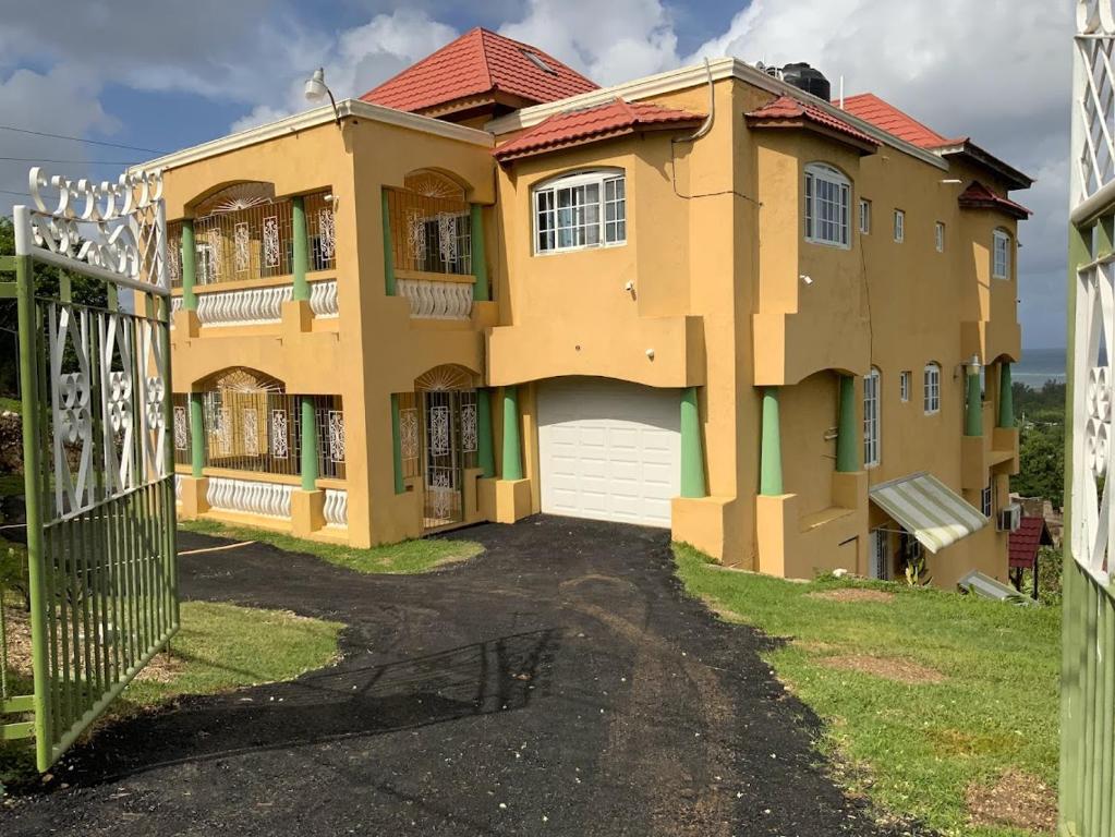 una gran casa amarilla con una puerta delante en Poinciana House, en Montego Bay