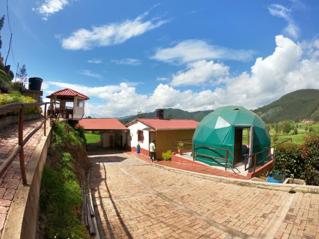une maison avec une tente verte sur une route en briques dans l'établissement Hermosa Finca El Porvenir, à Tibasosa