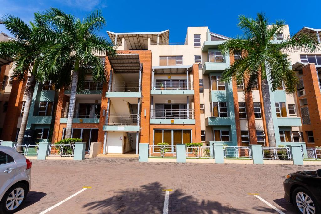 a building with palm trees in a parking lot at Unit 14, Capella Place in East Legon