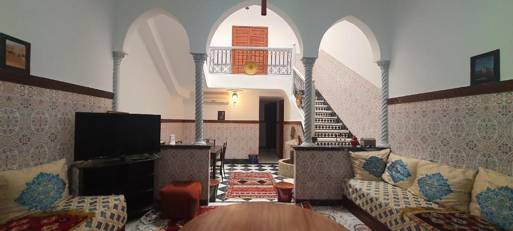 een woonkamer met een bank en een tv bij Quariya Assiyahiya Riad Camilia in Marrakesh