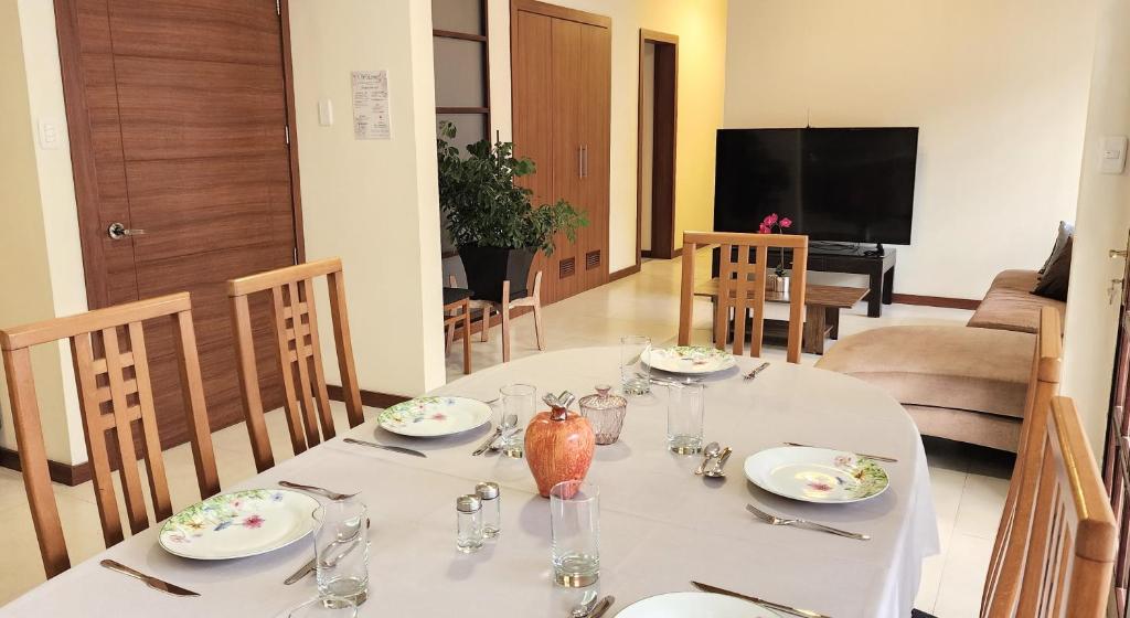 a dining room with a white table and a television at Grandioso Apartamento. in Quito
