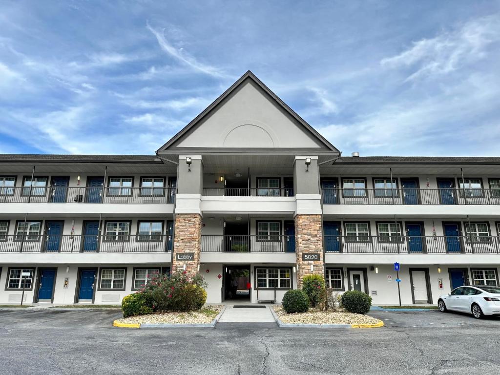 een groot gebouw met een auto geparkeerd op een parkeerplaats bij Motel 6 Columbus, GA Columbus Airport in Columbus