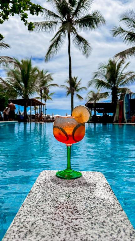 a glass with an orange sitting next to a swimming pool at Hotel Pousada Villa Zena - Frente ao Mar - Pé na areia in Arraial d'Ajuda