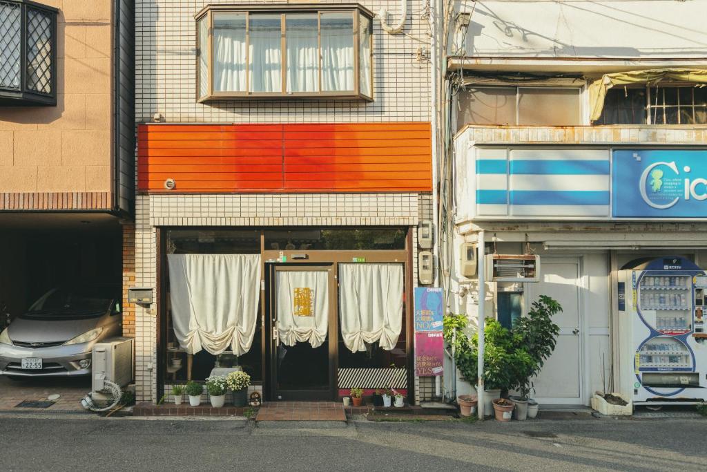 - un bâtiment avec une porte orange et des rideaux dans l'établissement 大同：14時からお泊まり, à Osaka