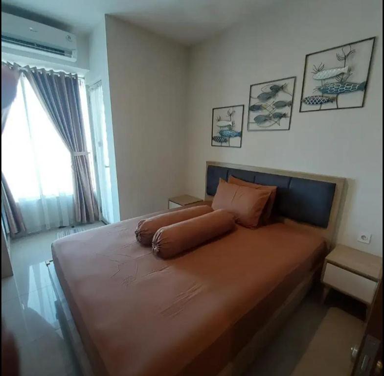 a bedroom with a large orange bed with a window at Transit 3jam Apartemen Grand Kamala lagoon bekasi in Pekayon Satu