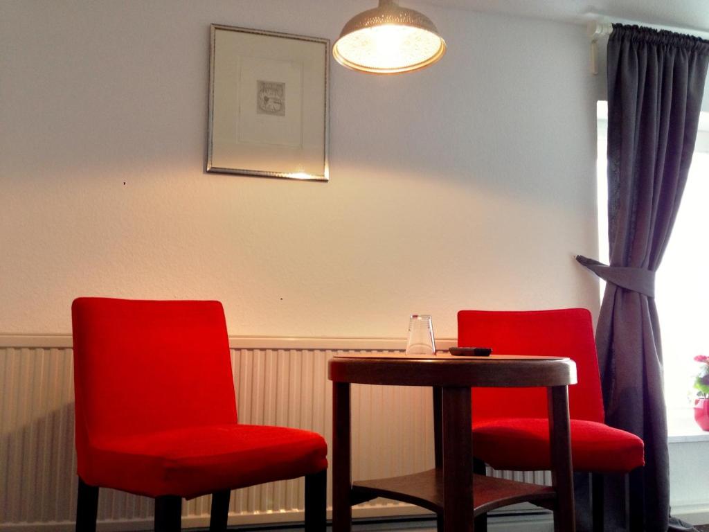 two red chairs and a table in a room at Pension Flughafen Leipzig in Freiroda