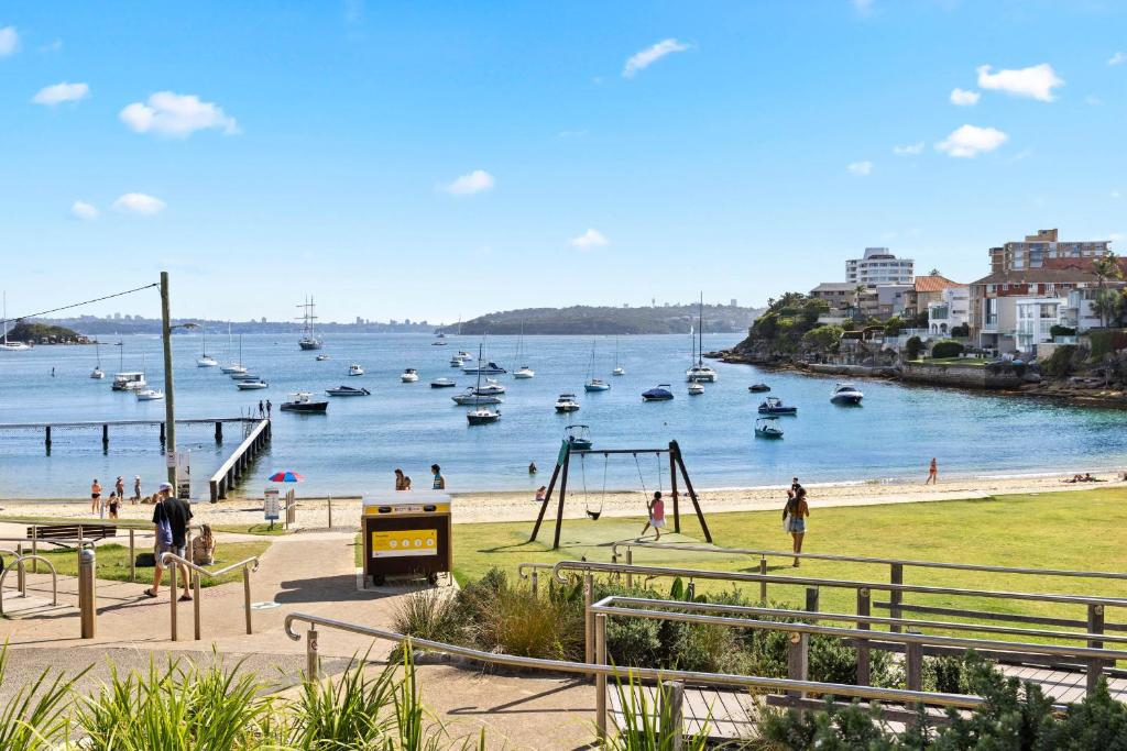 a group of people on a beach with boats in the water at Little Manly 3 Bedroom Sanctuary in Sydney
