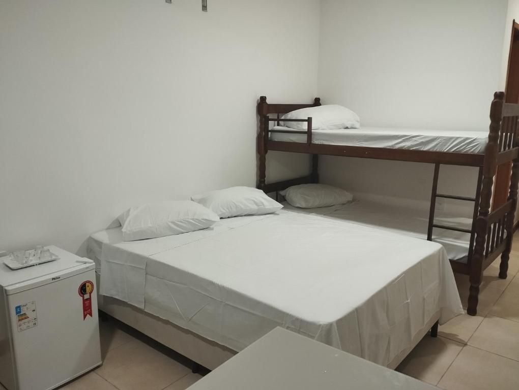Duas camas num quarto com um beliche e um frigorífico. em Flat para 4 pessoas bem pertinho da praia de Geriba em Búzios