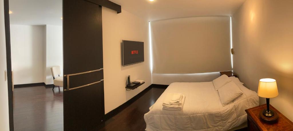 a small bedroom with a bed and a lamp at Suite con Jacuzzi - Torres el Bosque, Quito in Quito