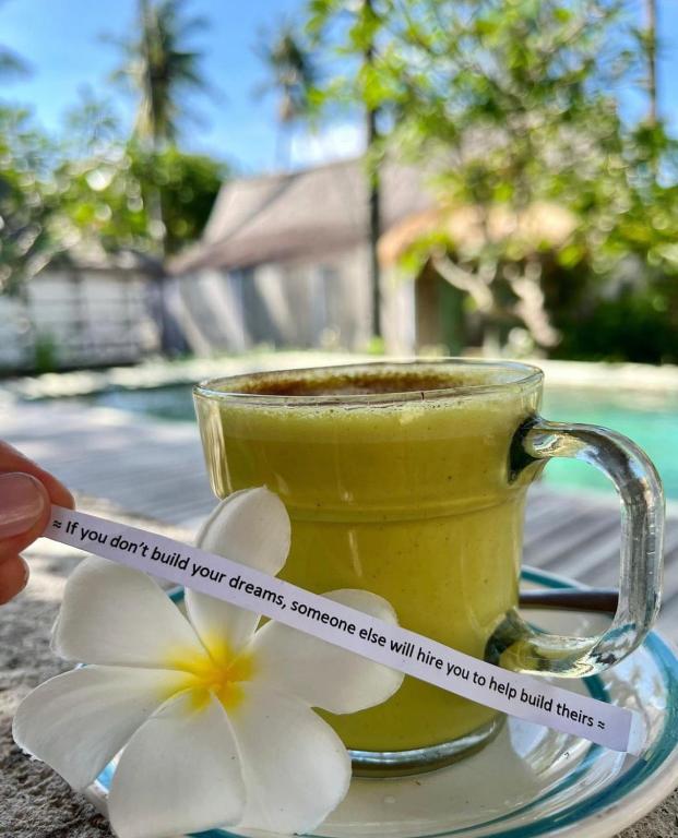 a cup of coffee with a flower on a plate at Captain Coconuts Gili Air in Gili Air