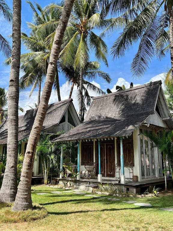 a house with palm trees in front of it at Captain Coconuts Gili Air in Gili Air